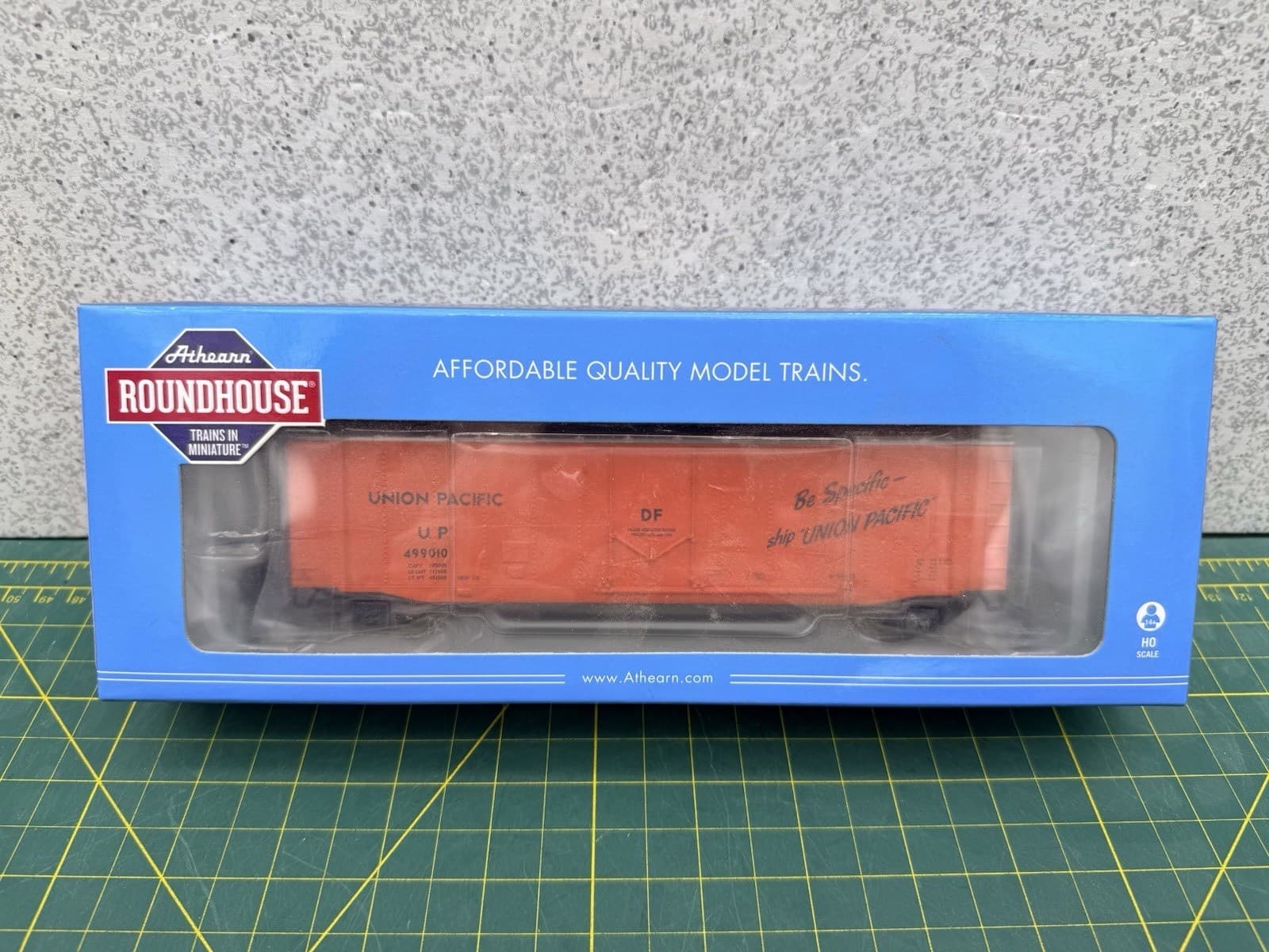 青い箱の窓に入った、オレンジの有蓋貨車の模型。箱に「ROUNDHOUSE」の札と「AFFORDABLE QUALITY MODEL TRAINS.」