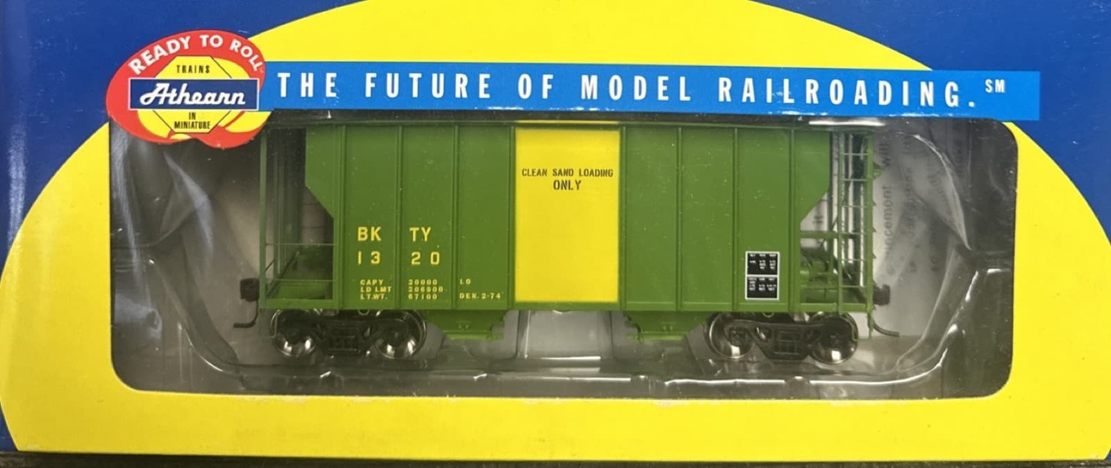 黄色い箱の窓に入った、緑のホッパー貨車の模型。箱の左上に「READY TO ROLL」の札がある