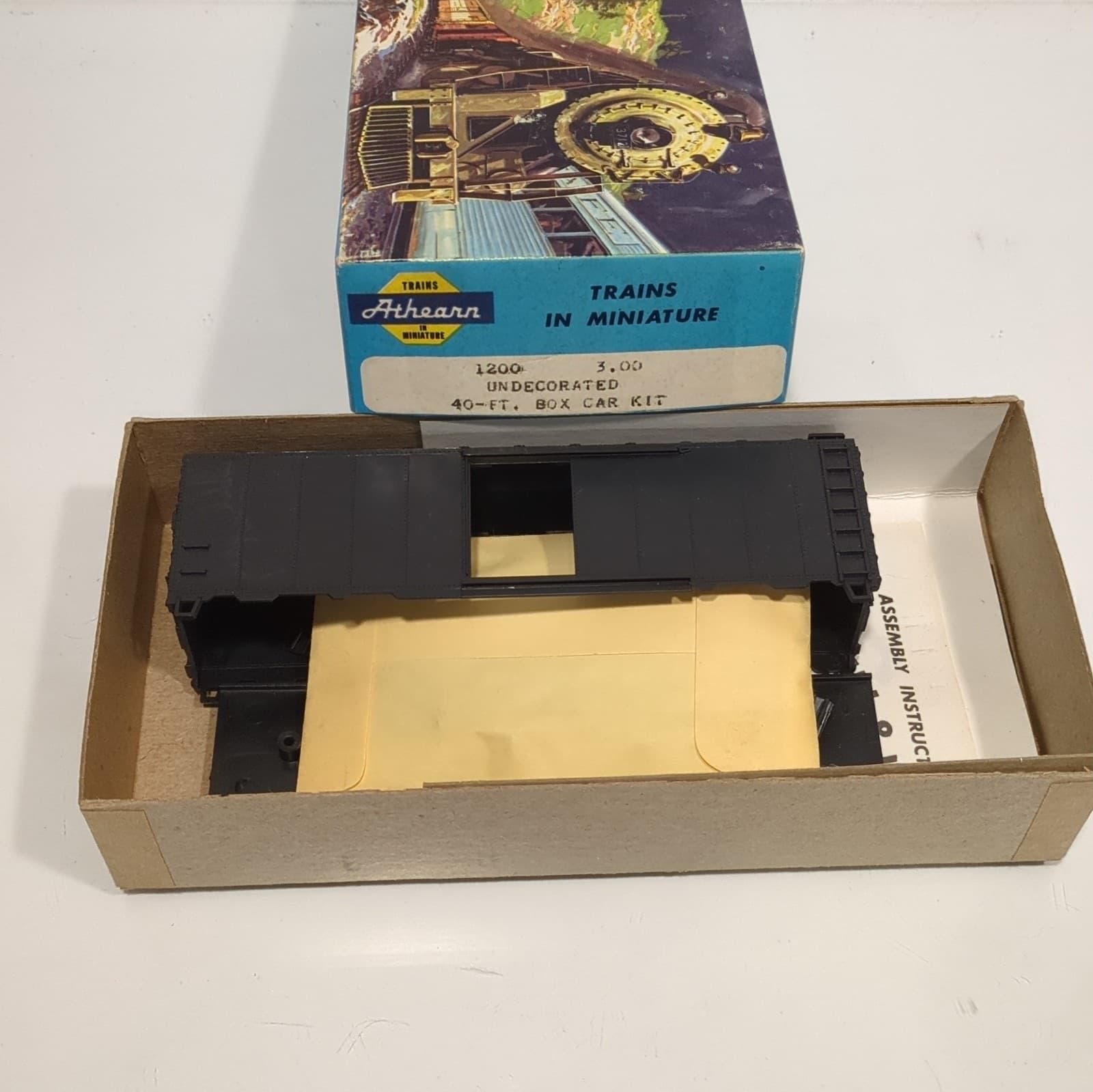 青い箱のふたに「TRAINS IN MINIATURE」と Athearn の札。手前の箱の中に、組み立て前の黒い貨車の車体