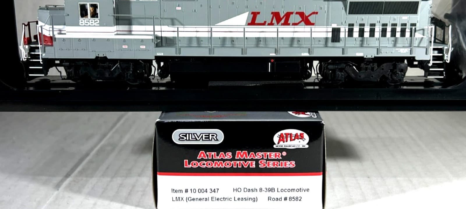 灰色の車体に赤い「LMX」の文字のディーゼル機関車の模型と、手前の黒い箱。箱に「SILVER」「ATLAS MASTER LOCOMOTIVE SERIES」「Item # 10 004 347」とある