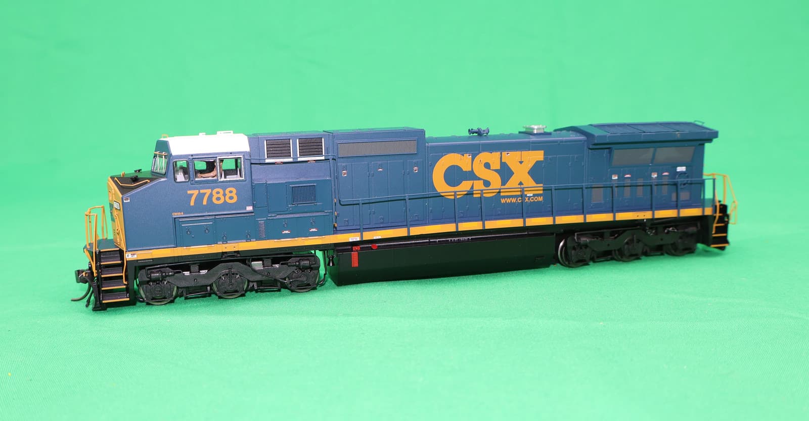 緑の背景に置いた、紺の車体に黄色い「CSX」と「7788」の文字のディーゼル機関車の模型