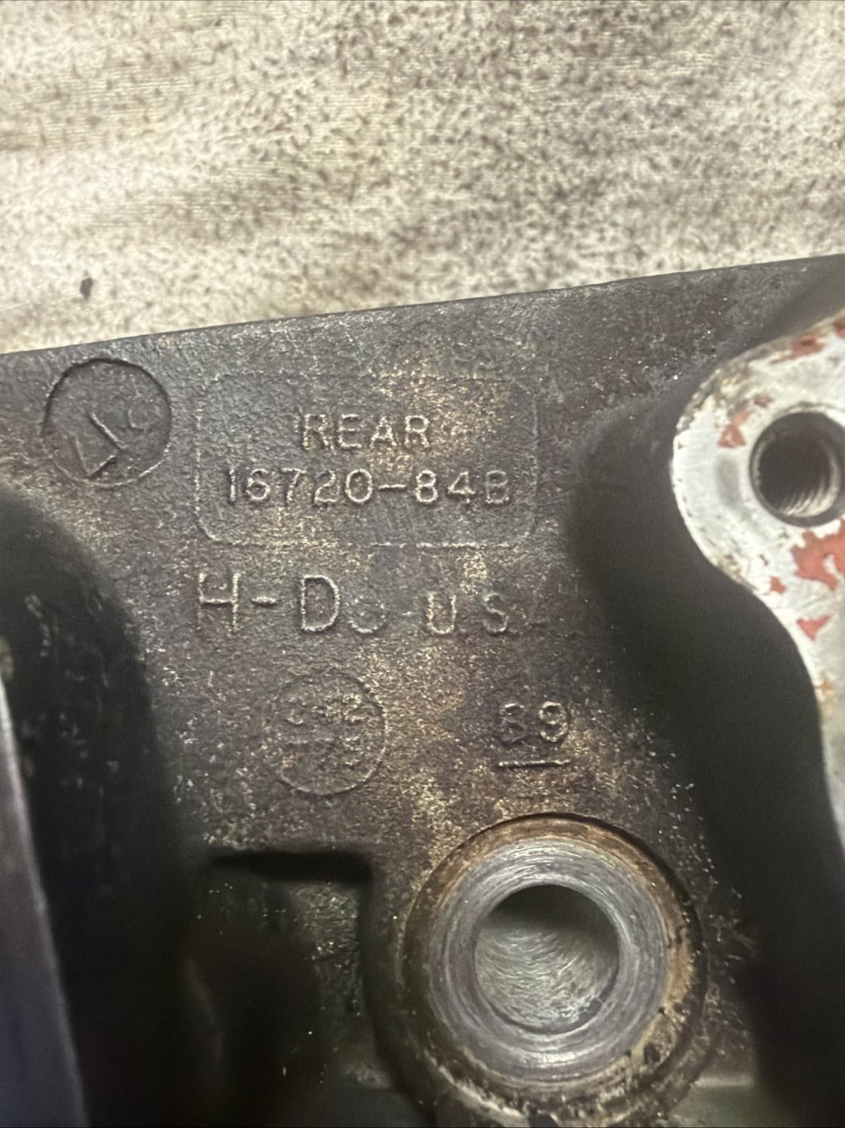 アルミの鋳物の表面の接写。「REAR」「16720-84B」「H-D U.S.」の浮き文字がある