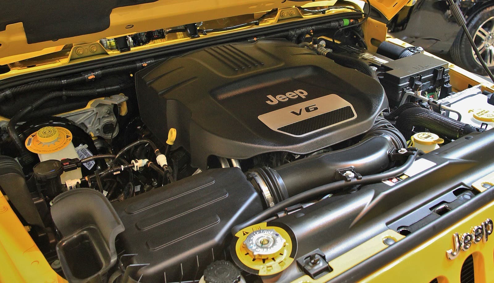 ラングラーJKのボンネットの中。黒いエンジンカバーに Jeep と V6 の文字