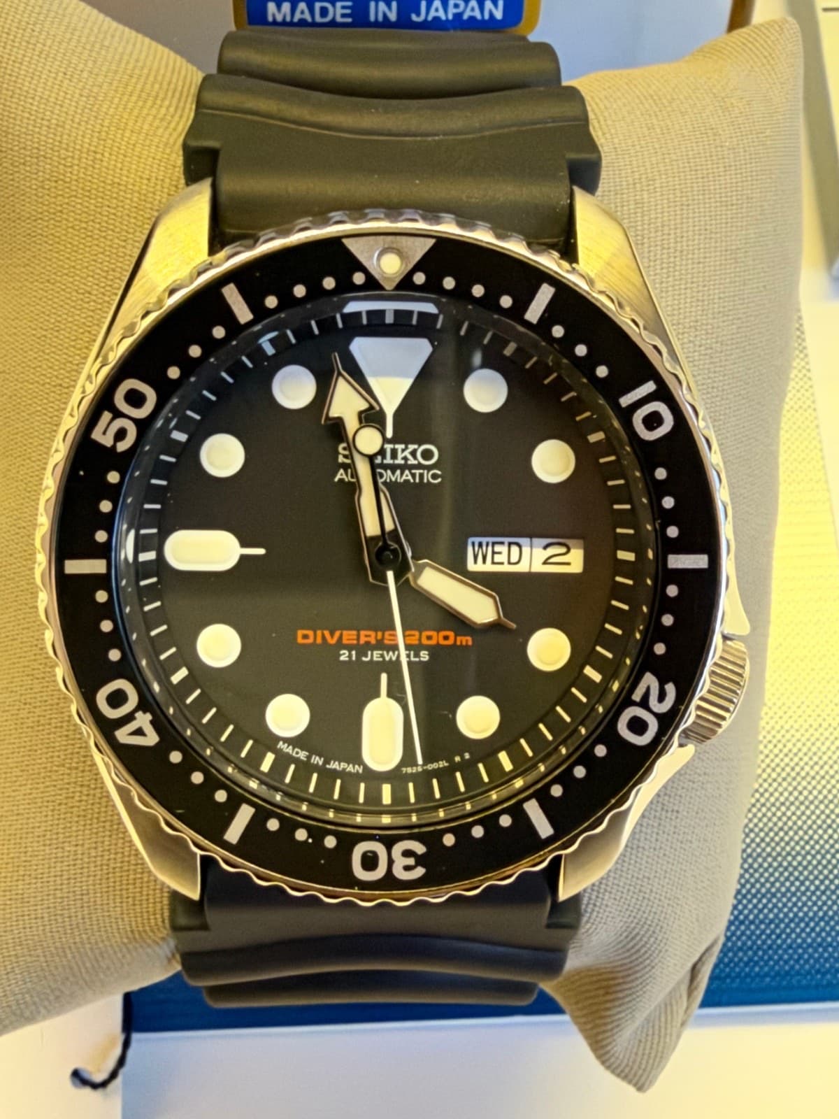 箱の中のクッションに巻いた黒いゴムのバンドの黒い文字盤のダイバーズ。上に「MADE IN JAPAN」の札が見える