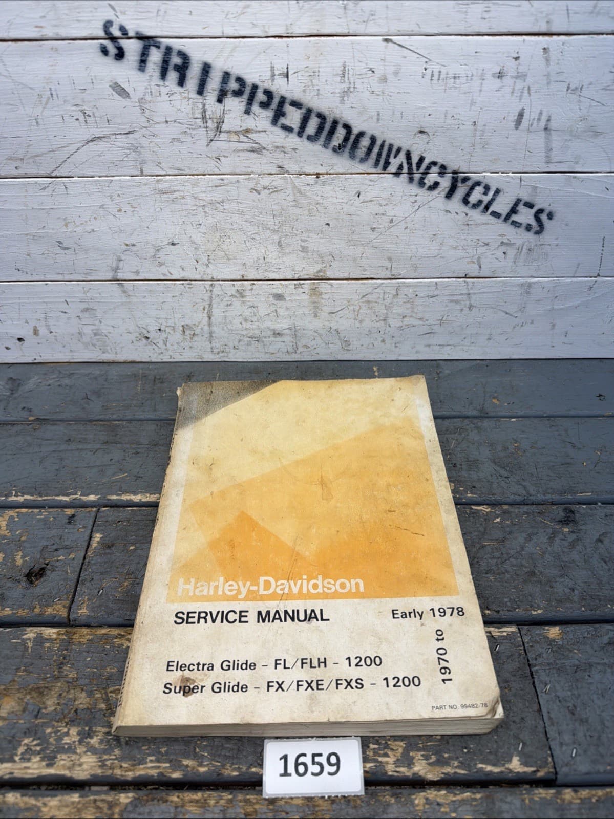 木の板の前に置いた、黄ばんだ表紙の冊子。表紙に Service Manual と Early 1978 の文字がある
