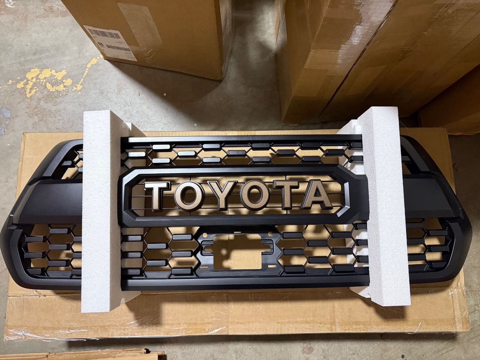 段ボールの上に置いた黒いグリル。中央に「TOYOTA」の大きな文字がある