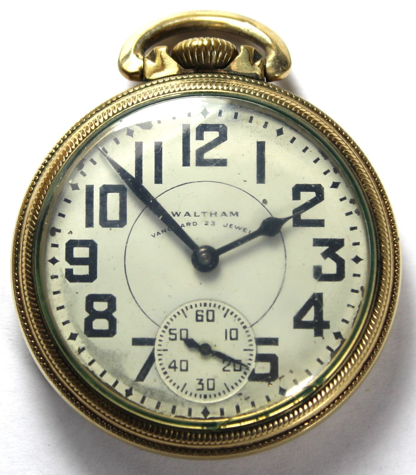 金色のケースの懐中時計の文字盤。白地に黒い太いアラビア数字と「WALTHAM」「VANGUARD 23 JEWELS」の文字、6時の位置に小さな秒針の目盛りがある